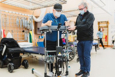 A patient uses a motorized walker with help from a physiotherapist