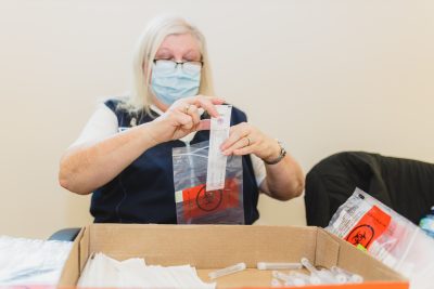 volunteer putting nasal swap into a bio hazard bag