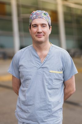 Dr. John Donnellan, dressed in scrubs, standing outdoors