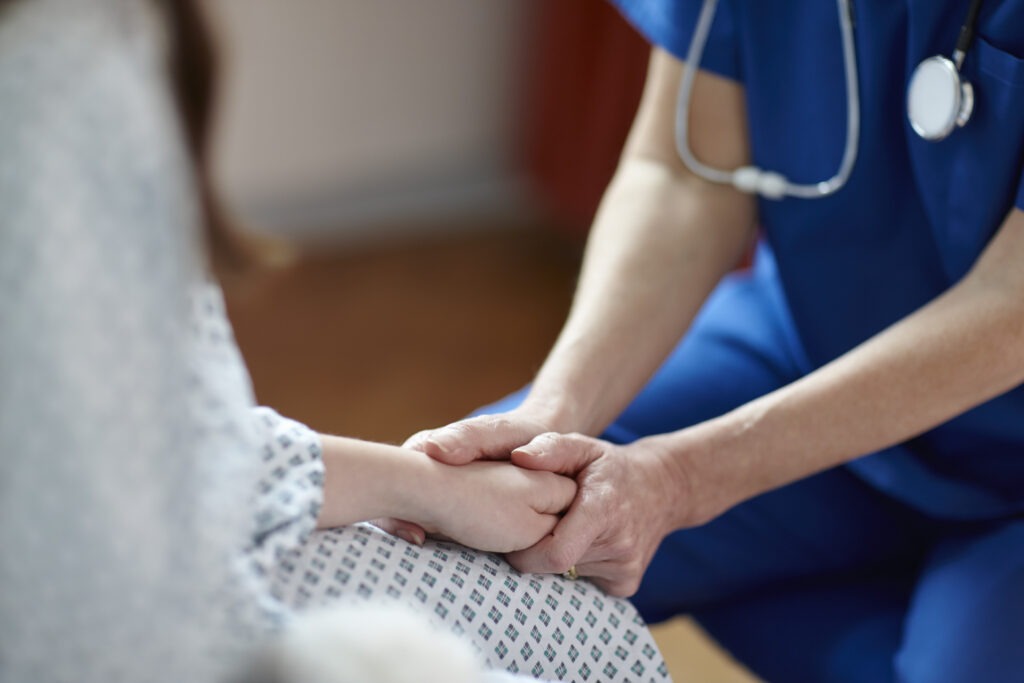 Close up photo of a nurse holding a patient's hand