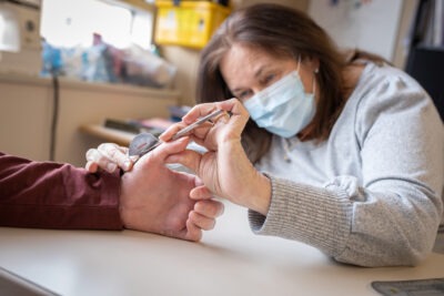 An HHS hand therapist measures a patient's hand.