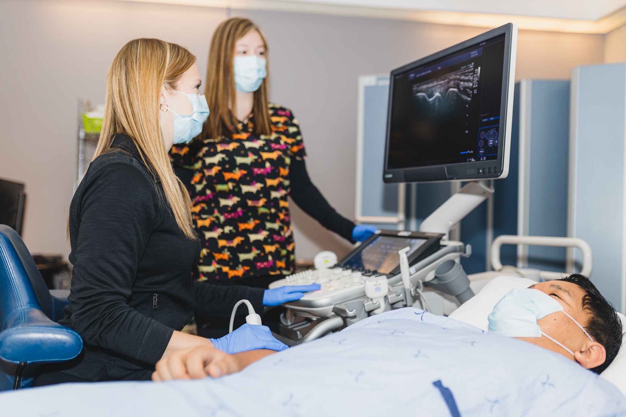 Two sonographers perform a musculoskeletal (MSK) ultrasound on a patient.