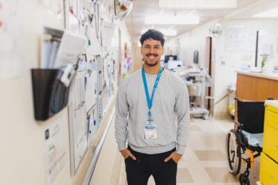 A clinical extern stands in a hospital hallway, smiling