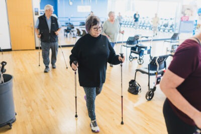 An older adult uses walking poles during an exercise class.