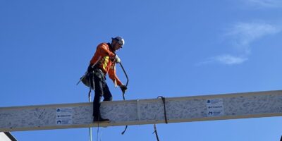 A construction worker helps secure the signed beam in the building’s framework.
