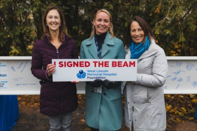 Photo from left to right of Kelly Campbell, HHS VP of Corporate Services and Capital Development; Catherine Duffin, WLMH Director of Community Programs and Site Administrator; and Dr. Joan Bellaire. They are holding a sign that reads, "I signed the Beam." West Lincoln Memorial Hospital Foundation.