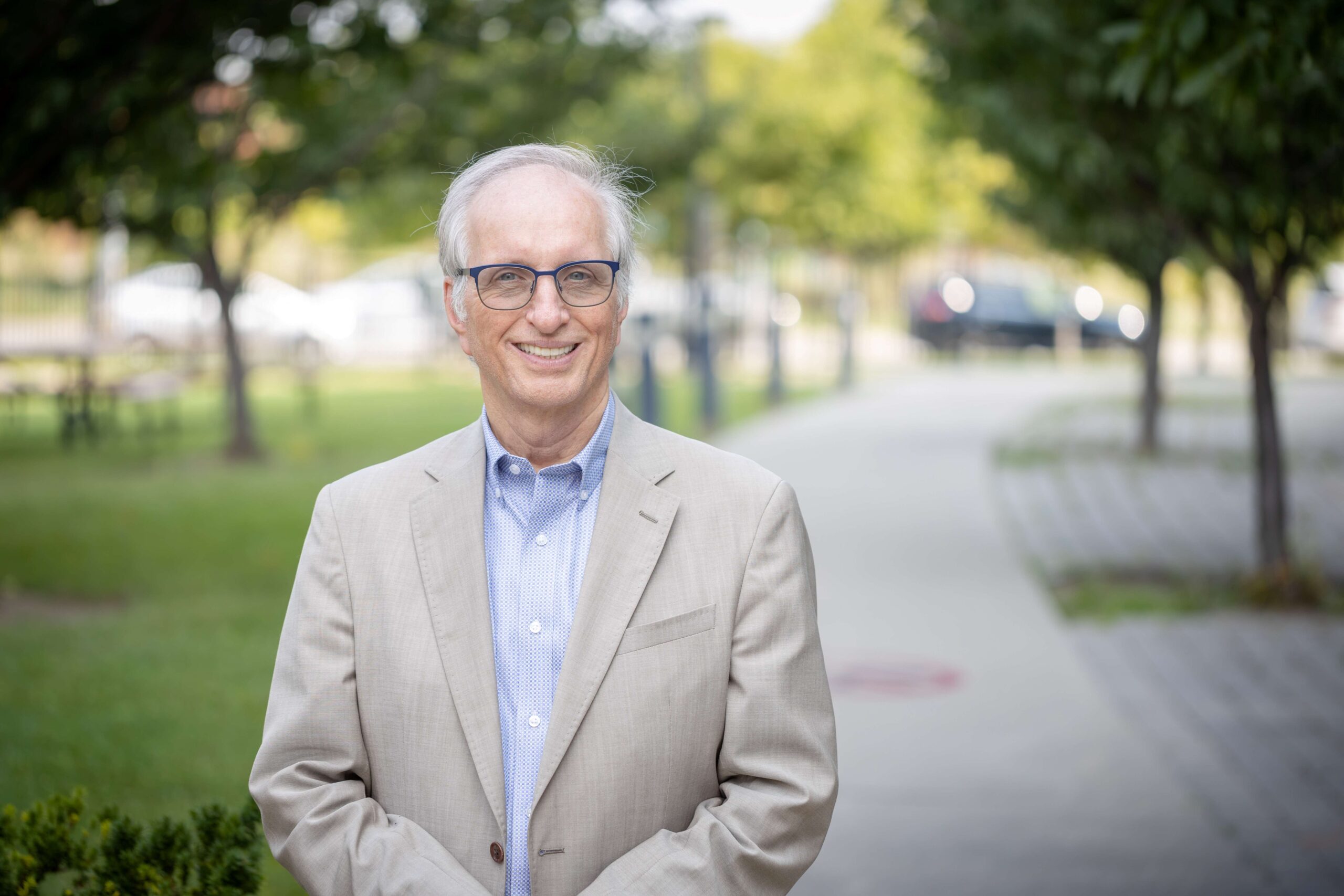 Dr. Hertzel Gerstein stands outdoors on a pathway, smiling