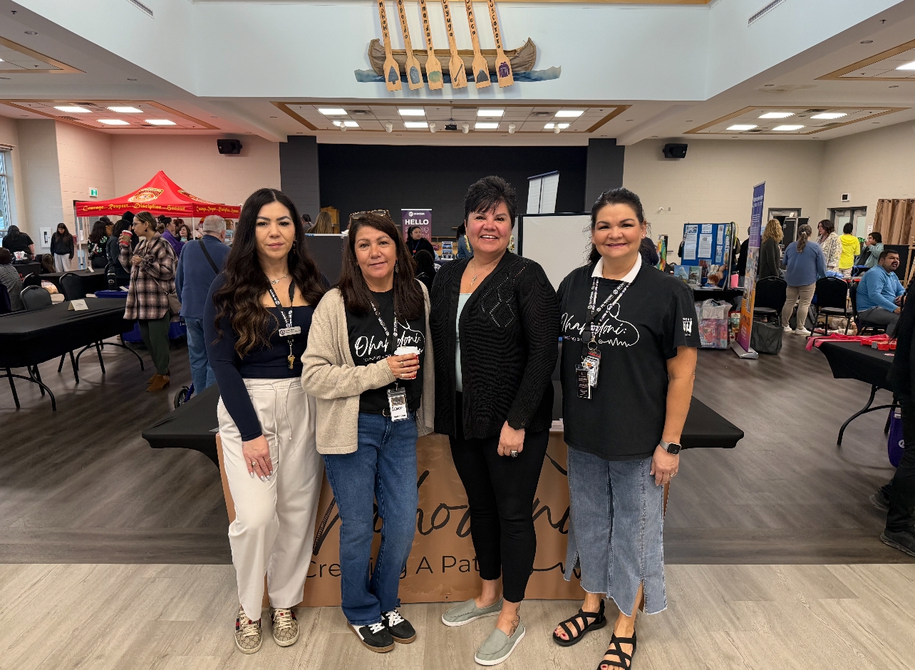 Four women stand together in front of a display table at the health careers event.