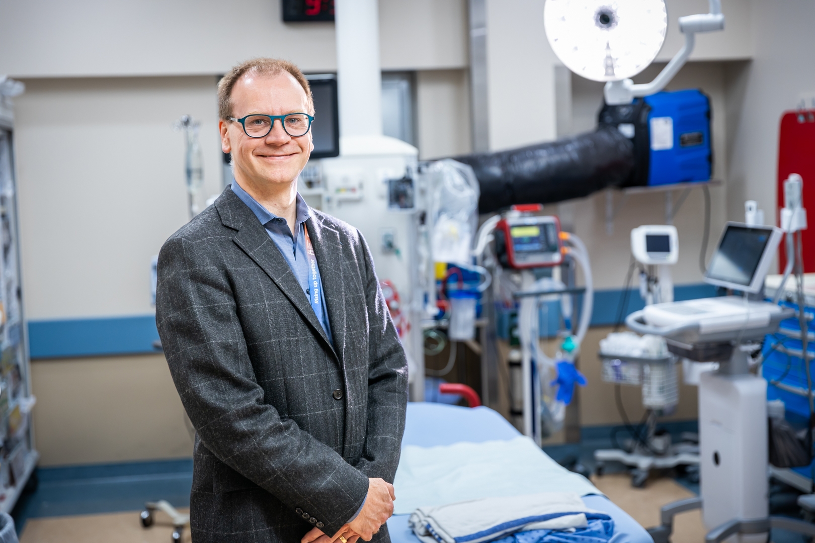 HHS trauma medical director Dr. Paul Engels stands in a trauma bay, in plain clothes, smiling.