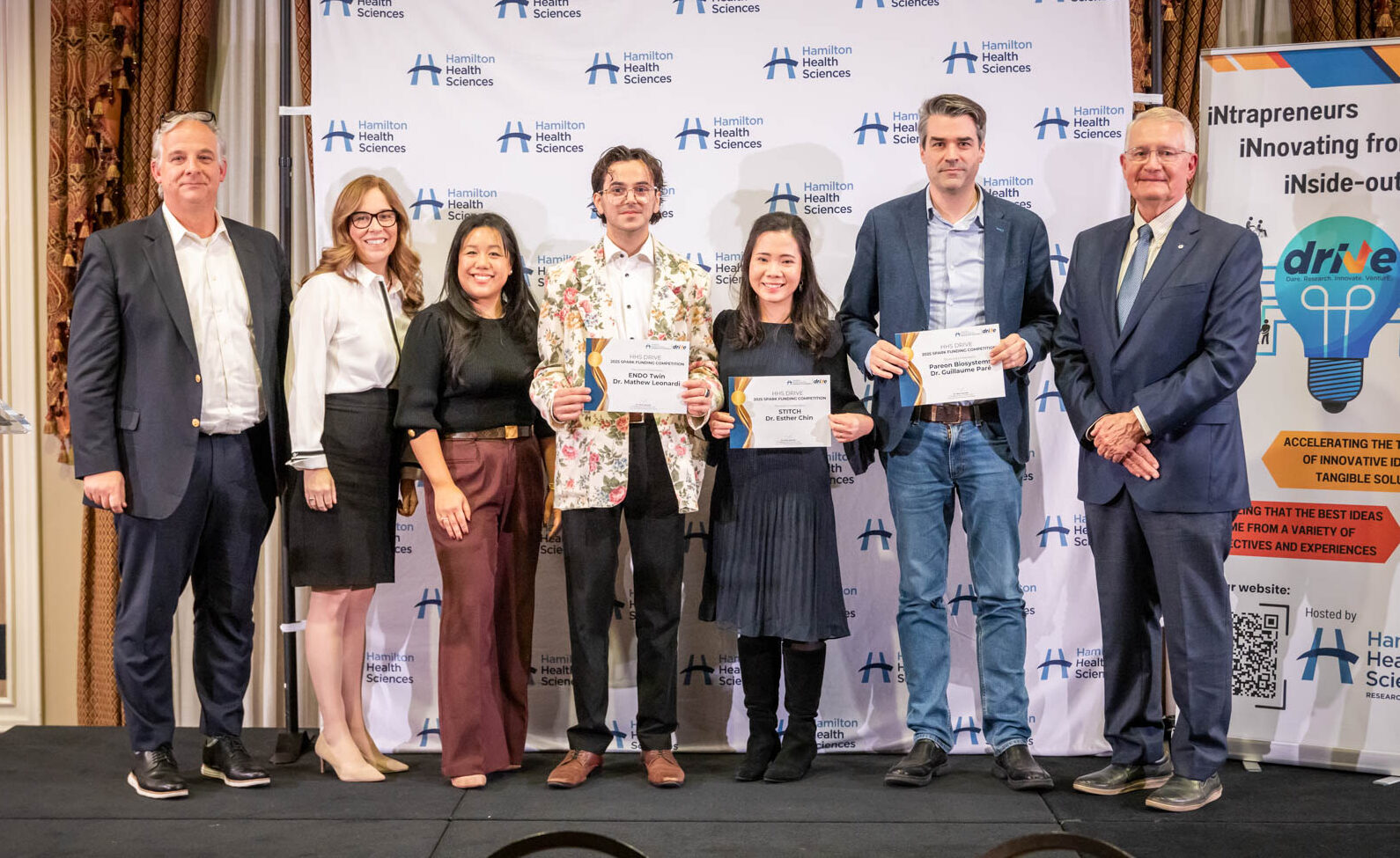 Highlights of the 2025 HHS Research & Innovation Awards of Excellence event included presenting DRIVE Spark awards to this year’s winners. Pictured from left to right: HHS Vice President of Research & Innovation, and Chief Scientific Officer, Dr. Marc Jeschke; Executive Director of Research Strategy and Operations, Katie Porter; Manager of Research Development, Innovation and Partnerships, Andrea Lee; Shay Freger (accepting for DRIVE Spark winner Dr. Mathew Leonardi; DRIVE Spark winners Dr. Esther Chin and Dr. Guillaume Paré; and Dr. John Kelton, Executive Director of McMaster University’s Heersink School of Biomedical Innovation and Entrepreneurship.